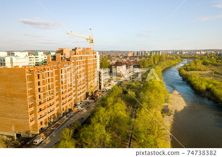 Aerial view of tall residential apartment buildings under construction and Bystrytsia river in Ivano-Frankivsk city, Ukraine. 74738382
