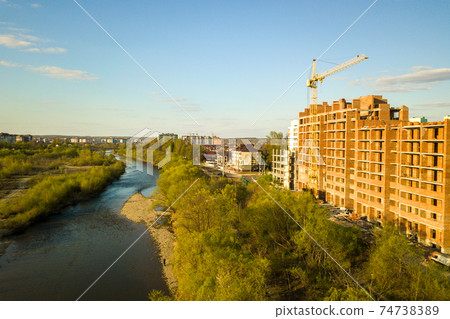 Aerial view of tall residential apartment buildings under construction and Bystrytsia river in Ivano-Frankivsk city, Ukraine. 74738389