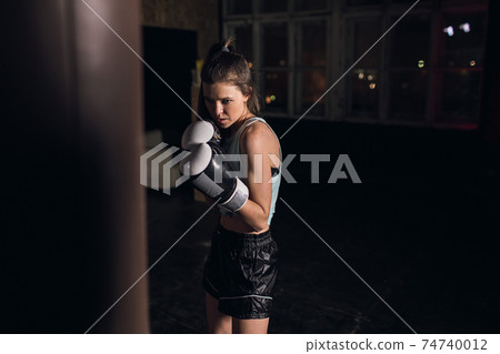 cool female fighter in boxing gloves trains in the gym. Mixed martial arts 74740012