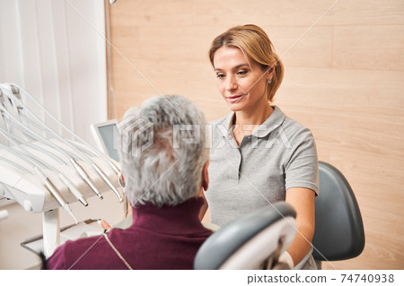 Man looking concerned at his dentist while listening Man looking concerned at his dentist while listening 74740938