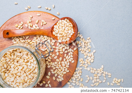 Flat lay. Glass jar with Siberian cedar nuts standing on a wooden stand.  74742134