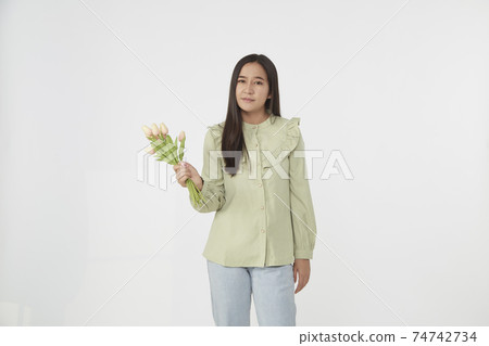 Spring Beautiful cheerful girl smiling and holding a bouquet of tulip flowers. Young happy woman. Surprise at the 8 March International Women's Day. 74742734