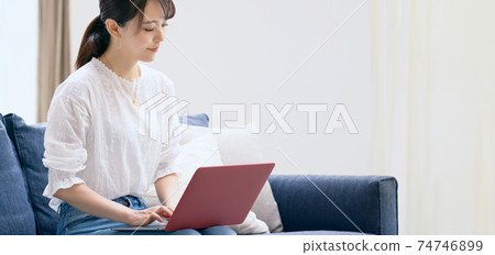 A lady who uses a laptop in the living room A lady who uses a laptop in the living room 74746899