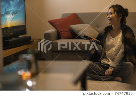 Young woman watching tv at night 74747933