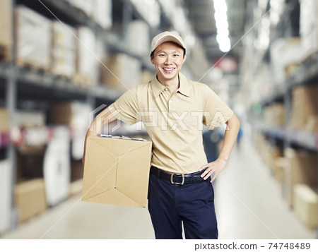portrait of a young warehouse worker carrying a carton box portrait of a young warehouse worker carrying a carton box 74748489