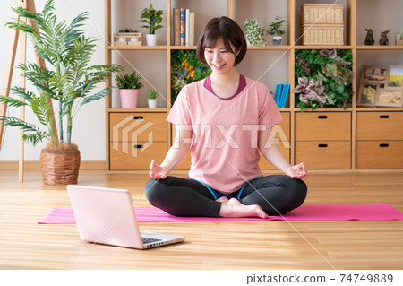 Online yoga young woman doing yoga poses in the living room Online yoga young woman doing yoga poses in the living room 74749889