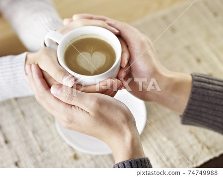 hands of young lovers holding a cup of coffee 74749988