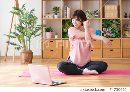 在線瑜伽年輕女子在客廳裡伸展 74750611