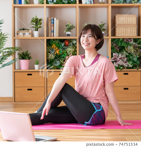 Online yoga Young woman doing yoga poses while looking at a computer in the living room Square Online yoga Young woman doing yoga poses while looking at a computer in the living room Square 74751534