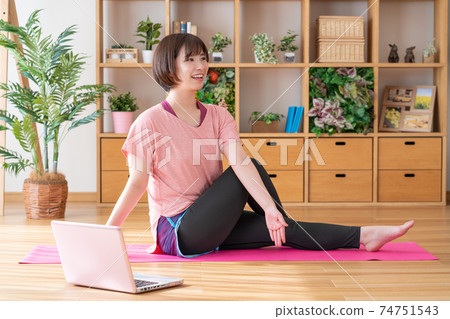 Online yoga A young woman doing yoga poses while looking at a computer in the living room Online yoga A young woman doing yoga poses while looking at a computer in the living room 74751543