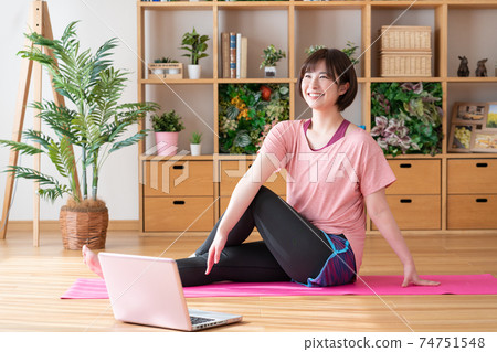 Online yoga A young woman doing yoga poses while looking at a computer in the living room Online yoga A young woman doing yoga poses while looking at a computer in the living room 74751548