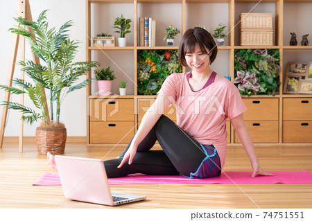 Online yoga A young woman doing yoga poses while looking at a computer in the living room Online yoga A young woman doing yoga poses while looking at a computer in the living room 74751551