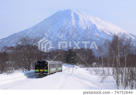 Regular train heading to Otaru with Mt. Yotei in the background 74752644