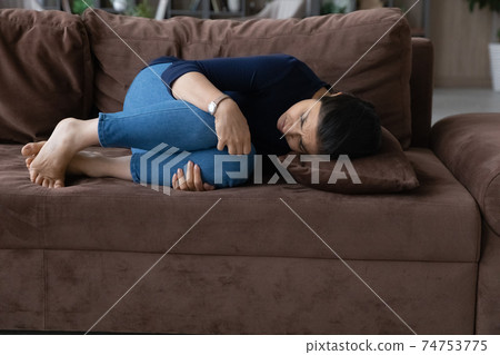 Unwell Indian woman lying suffer from stomachache Unwell Indian woman lying suffer from stomachache 74753775