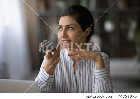 Millennial Indian woman activate digital voice assistant on cellphone 74753959