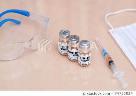 A bottle of of coronavirus vaccine. a dialed syringe on the table. A bottle of of coronavirus vaccine. a dialed syringe on the table. 74755024