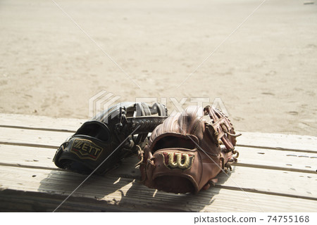 Gloves placed on a bench in a high school baseball practice scene 74755168