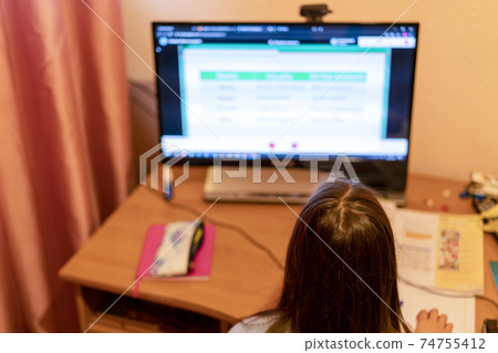 Smart preteen schoolgirl doing her homework with digital tablet at home. Child using gadgets to study. Education and learning for kids. Homeschooling during quarantine. Stay at home entertainment 74755412