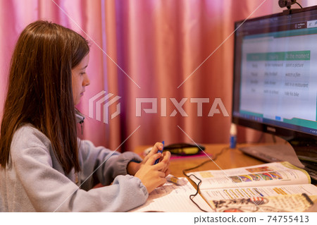 Smart preteen schoolgirl doing her homework with digital tablet at home. Child using gadgets to study. Education and learning for kids. Homeschooling during quarantine. Stay at home entertainment 74755413