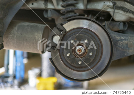 The hub of a wheel in a car service. Suspended car with no wheels. Suspension of car in service room.The car lift up by lifter for maintenance suspension and cleaning parts. Close up The hub of a wheel in a car service. Suspended car with no wheels. Suspension of car in service room.The car lift up by lifter for maintenance suspension and cleaning parts. Close up 74755440