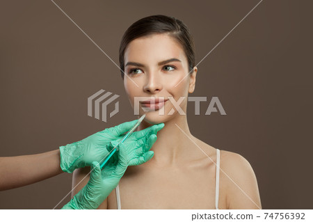Lip augmentation. Doctor holding syringe near beautiful female face 74756392