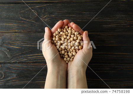 Female hands hold fresh chickpea on wooden background 74758198