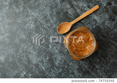 Jar with zucchini caviar and wooden spoon on black smokey background Jar with zucchini caviar and wooden spoon on black smokey background 74758548