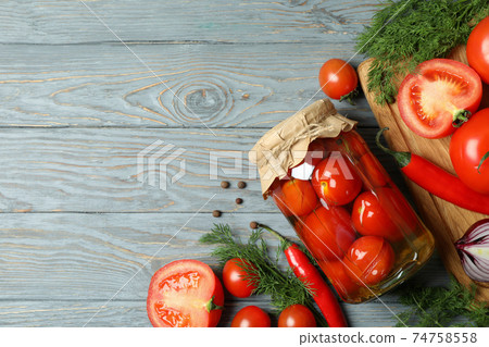 Jar of pickled tomatoes and ingredients on wooden table Jar of pickled tomatoes and ingredients on wooden table 74758558