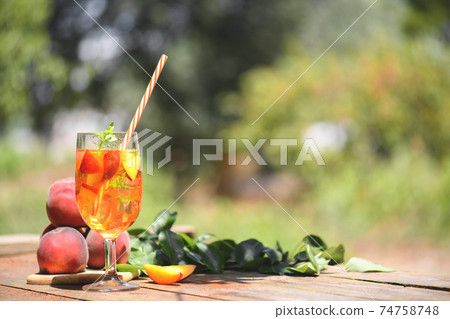 Fresh Homemade Peach Tea with Mint and Peach Slices, cold fruit drink outdoors 74758748