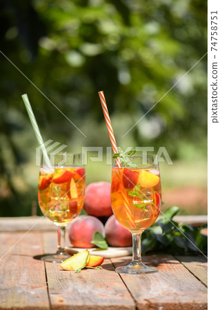 Fresh Homemade Peach Tea with Mint and Peach Slices, cold fruit drink outdoors 74758751