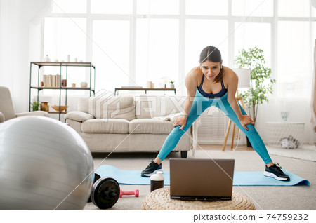 Girl standing at laptop, online fitness training 74759232