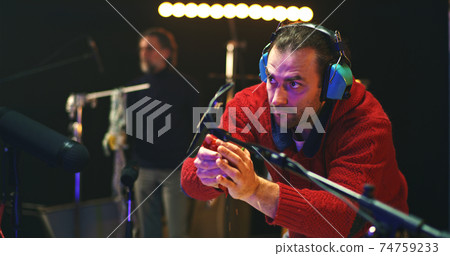 Male colleagues creating various sounds for movie in studio 74759233
