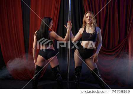 Two sensual striptease dancers, pole dance Two sensual striptease dancers, pole dance 74759329