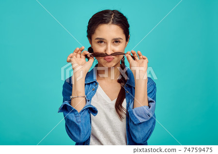 Funny young woman shows mustache, positive emotion Funny young woman shows mustache, positive emotion 74759475