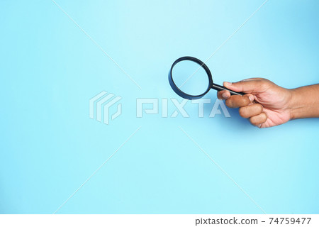 hand holding magnifying glass on blue with copy space hand holding magnifying glass on blue with copy space 74759477