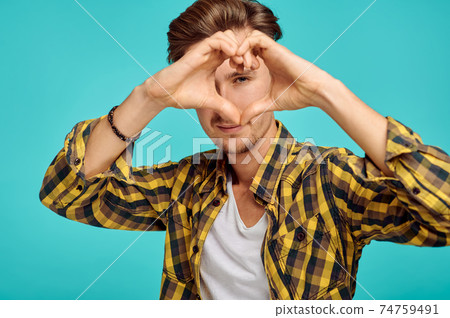 Young man shows heart sign, blue background 74759491