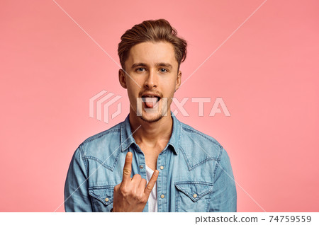 Man shows his tongue, pink background, emotion 74759559