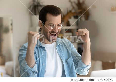 Excited millennial triumph with online win on computer Excited millennial triumph with online win on computer 74760069