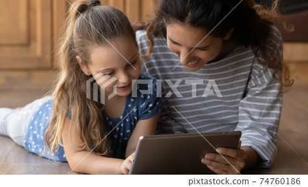 Close up smiling mother and little daughter using tablet together Close up smiling mother and little daughter using tablet together 74760186