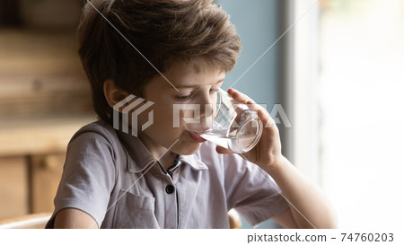 Close up little boy drinking pure fresh water, holding glass 74760203