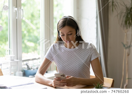 Caucasian woman in headphones talk on video call on smartphone 74760268