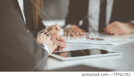 Unknown businessmen and woman sitting, working and discussing questions at meeting in modern office, close-up Unknown businessmen and woman sitting, working and discussing questions at meeting in modern office, close-up 74762761