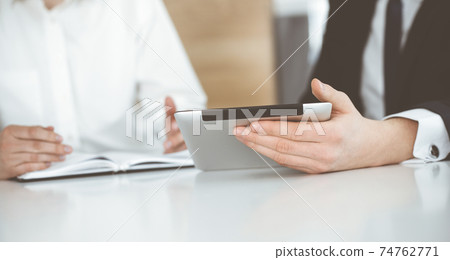 Unknown business people using tablet computer in modern office. Businessman or male entrepreneur is working with his colleague at the desk Unknown business people using tablet computer in modern office. Businessman or male entrepreneur is working with his colleague at the desk 74762771