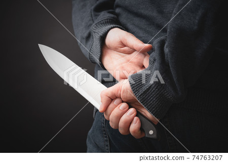 Murderer holding knife in his hand 74763207