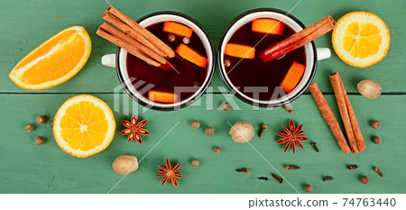 Mulled red wine with spices and fruits on a wooden table. Wide photo. Mulled red wine with spices and fruits on a wooden table. Wide photo. 74763440