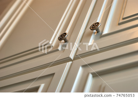 Classic white wardrobe with ornamental handles close-up Classic white wardrobe with ornamental handles close-up 74765053