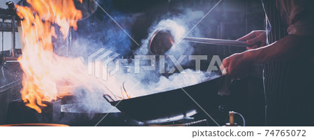 Chef stir fry busy cooking in kitchen Chef stir fry busy cooking in kitchen 74765072