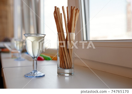 glass of wine and crunchy bread sticks 74765170