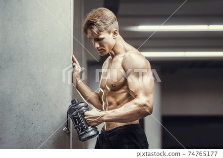 Bodybuilder drinking water after fitness workout 74765177