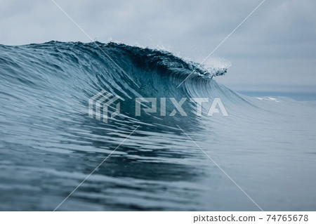 Perfect ocean waves with blue water cloudy sky. 74765678